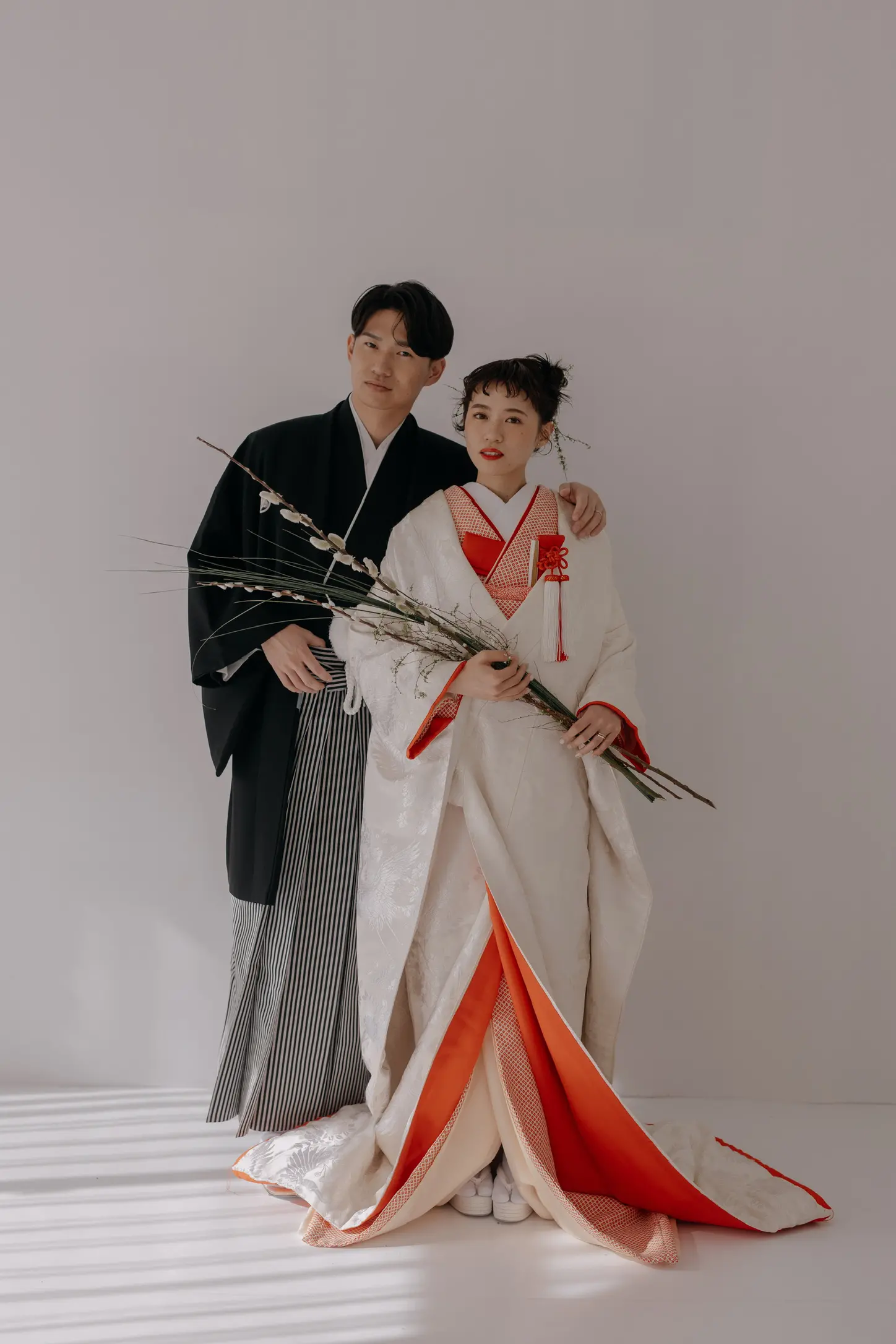 紋付き袴の新郎と色打掛の花嫁がお花を持って並ぶ和装の写真