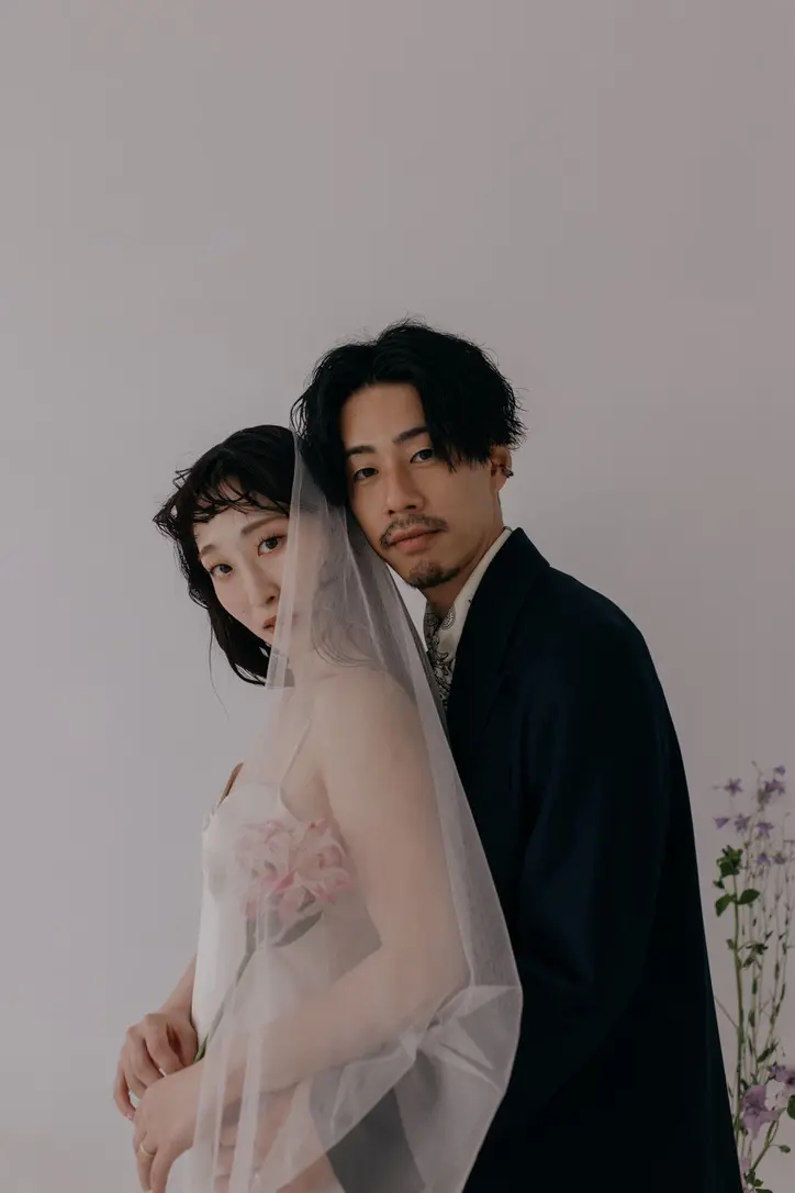 フラワー刺繍のウェディングドレスにベールの花嫁とスーツ姿の新郎が寄り添う洋装の写真