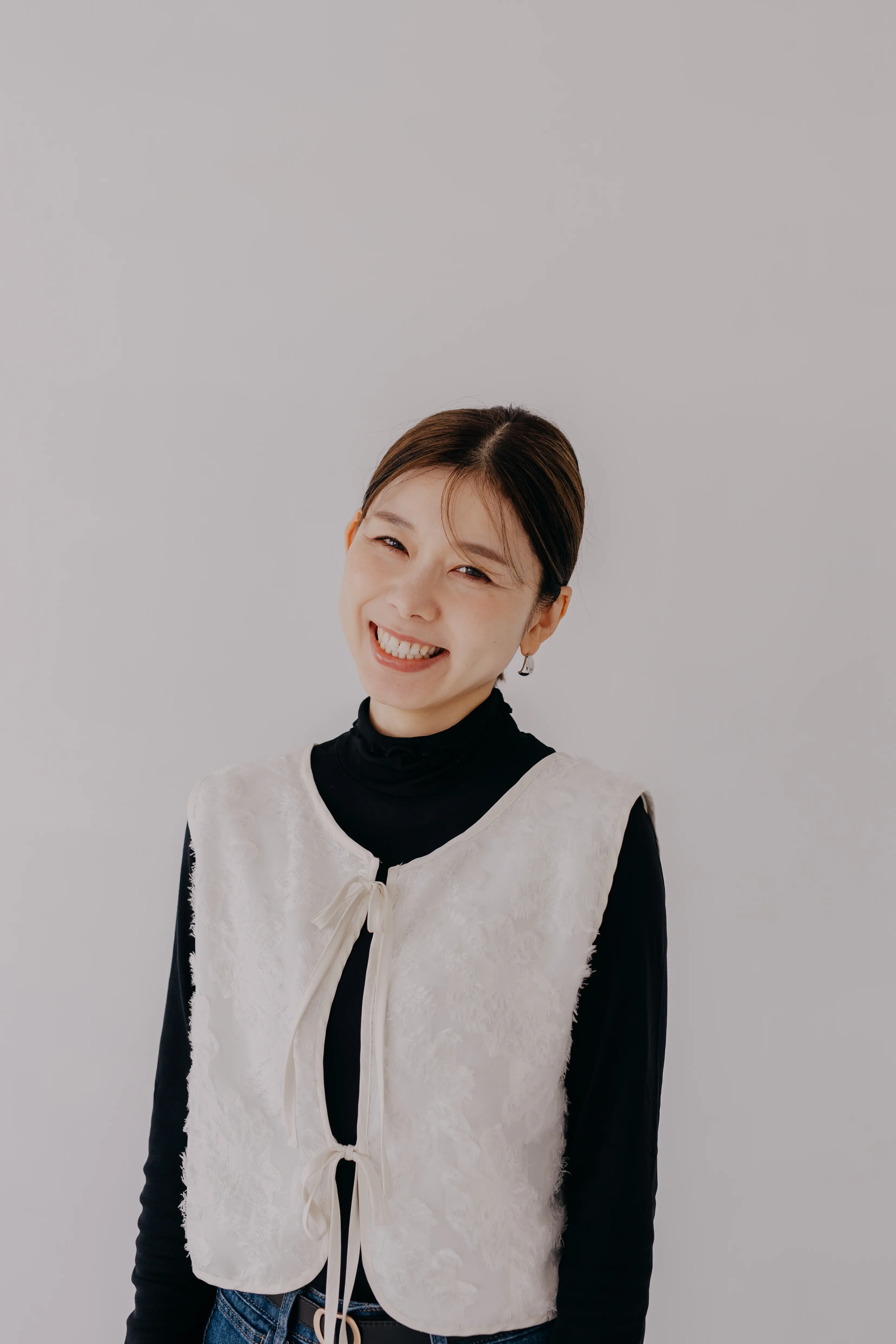 白いベストと黒タートルネックを着た女性のプロフィール写真